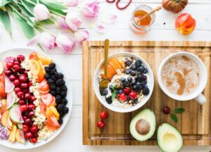 A kitchen table with a bowl of oatmeal, berries, nuts, and a glass of water in morning sunlight.